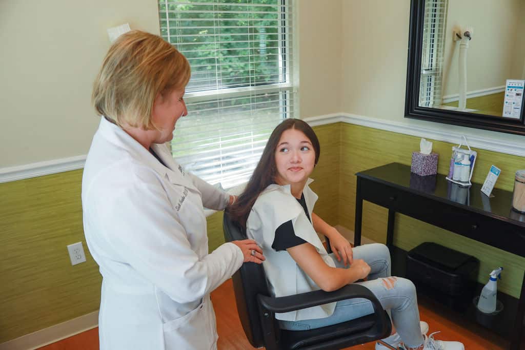 young girl at head lice removal clinic talking to lice removal professional