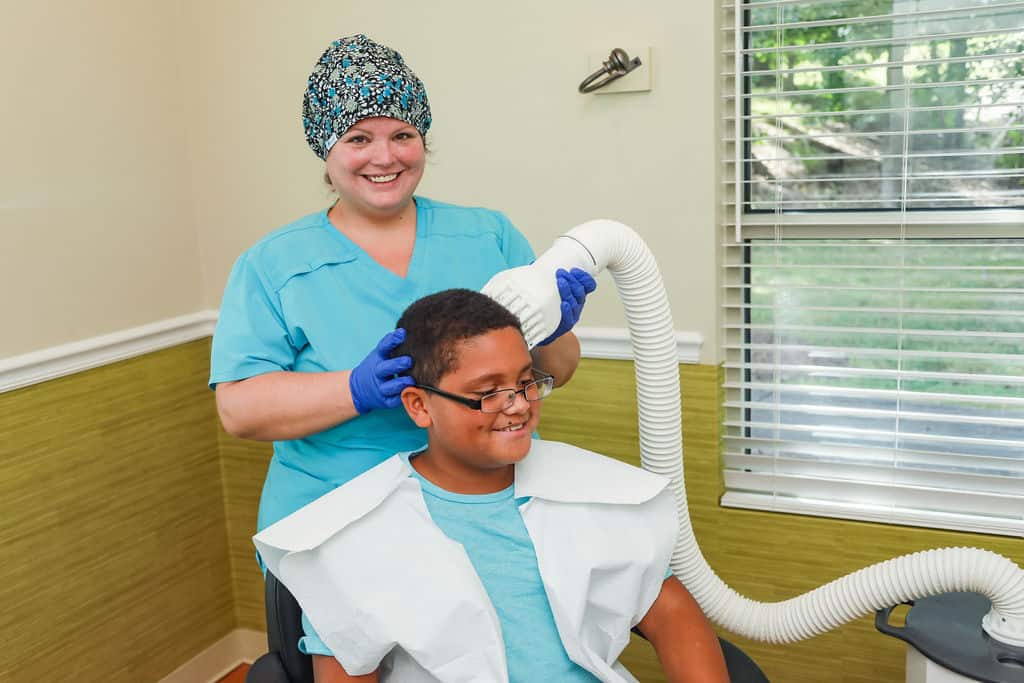 lice removal technician using flosonix device to treat a child